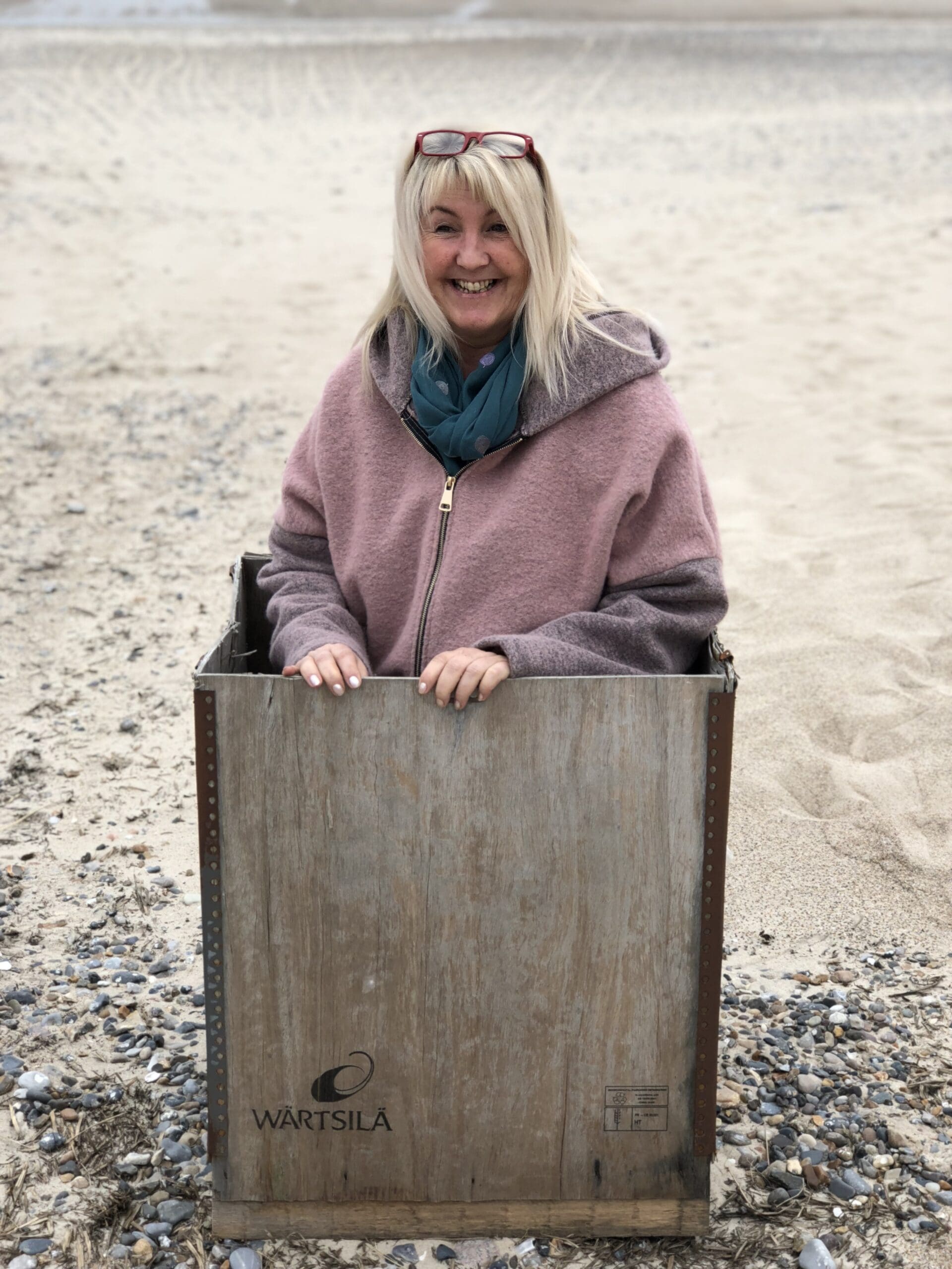 Forfatter Lotte Jensen i en kasse på stranden ved vesterhavet